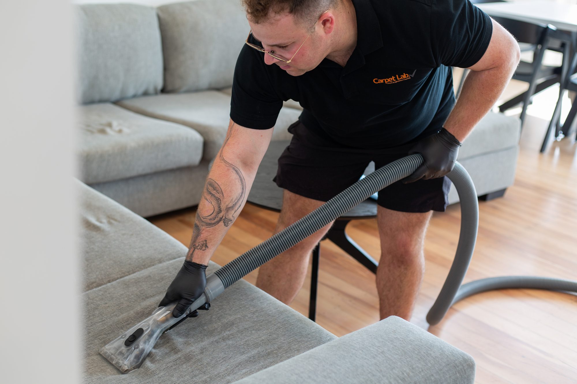 Carpet Lab technician using extraction equipment to clean a fabric sofa